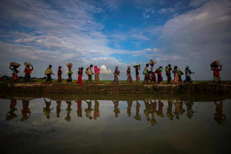 FILE PHOTO: Rohingya refugees are reflected in rain water along an embankment next to paddy fields after fleeing from Myanmar into Palang Khali, near Cox's Bazar, Bangladesh November 2, 2017. REUTERS/Hannah McKay/File Photo